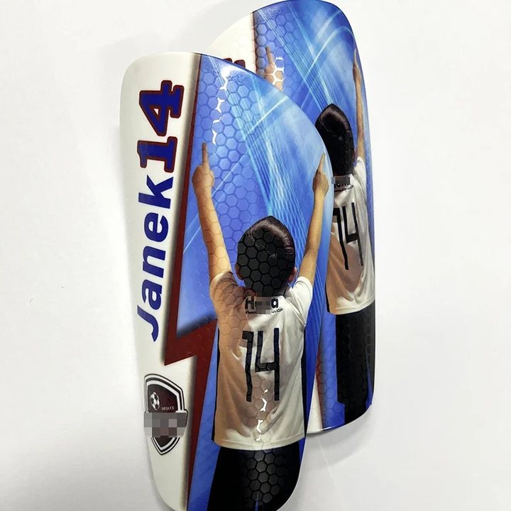 Honeycomb-textured shin guard pair printed 'Janek 14' with a player photo